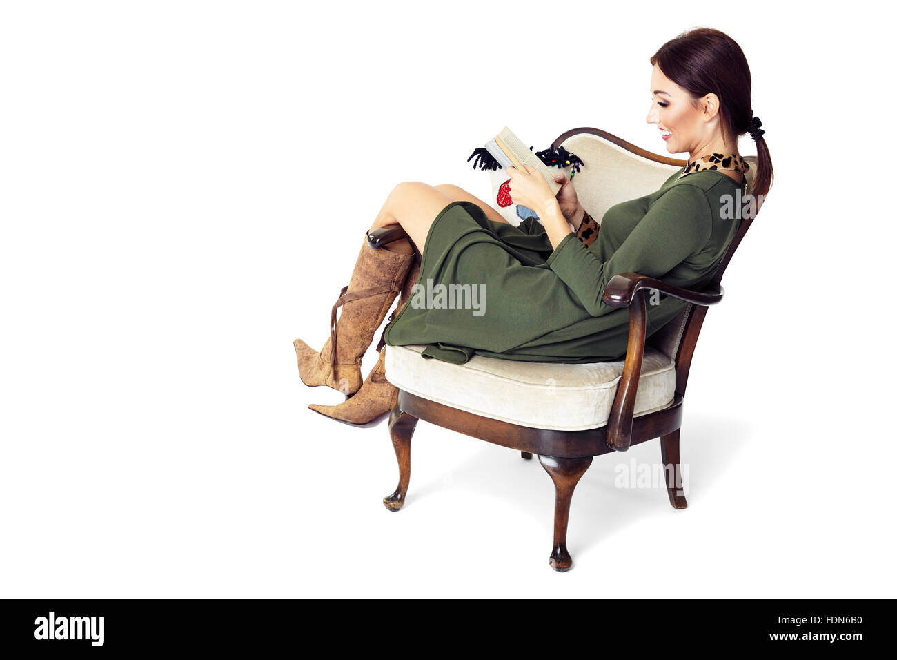 Cheerful woman sitting on chair and reading a book. Isolated on white background. Stock Photo