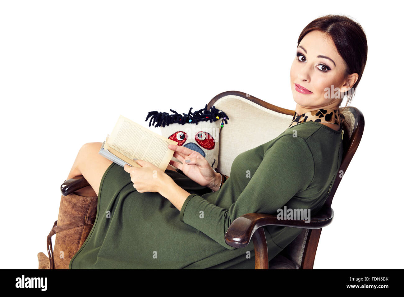 Young woman sitting on chair, holding a book and looking at you. Stock Photo