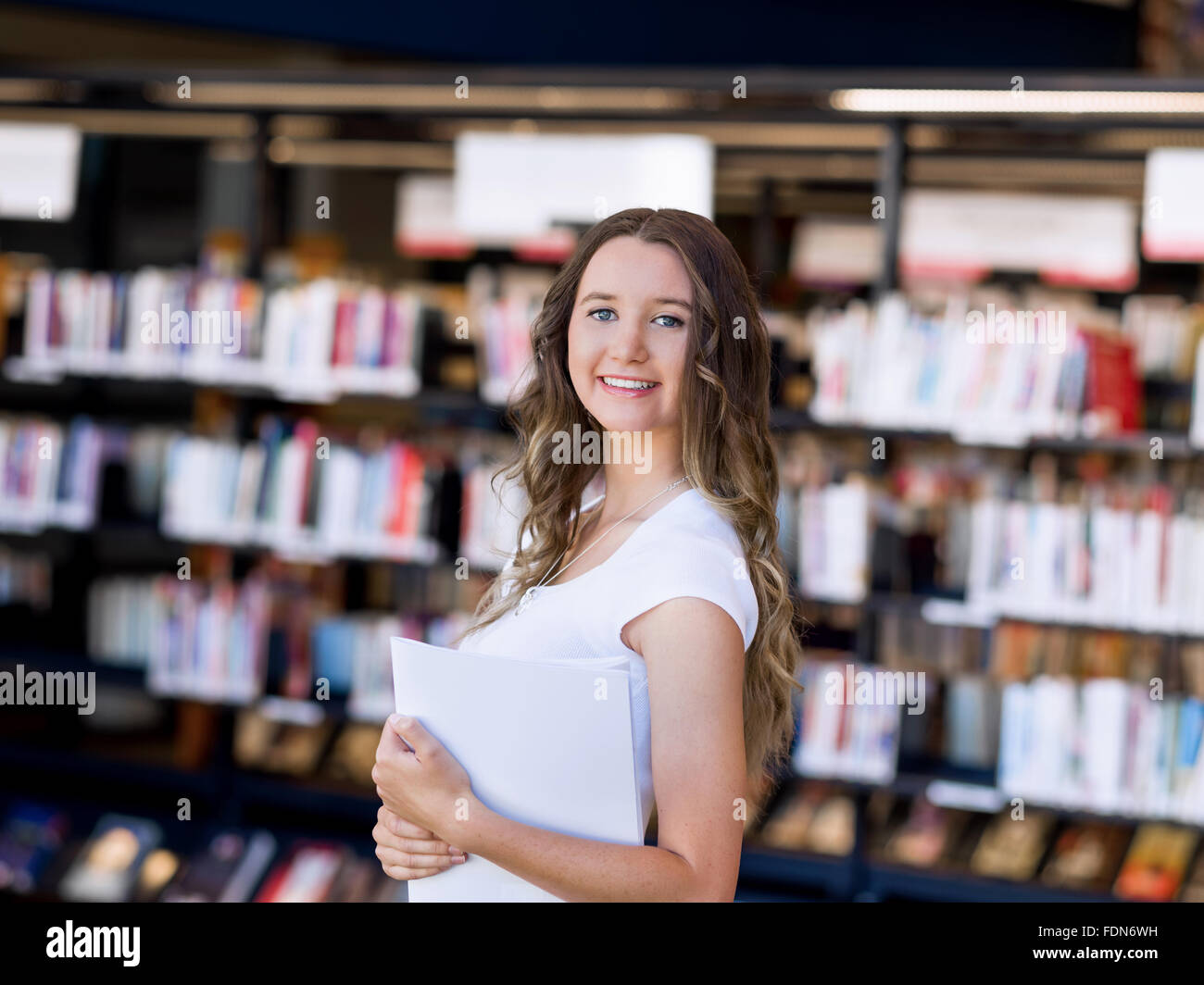 Happy young female student holding books at the library Stock Photo - Alamy