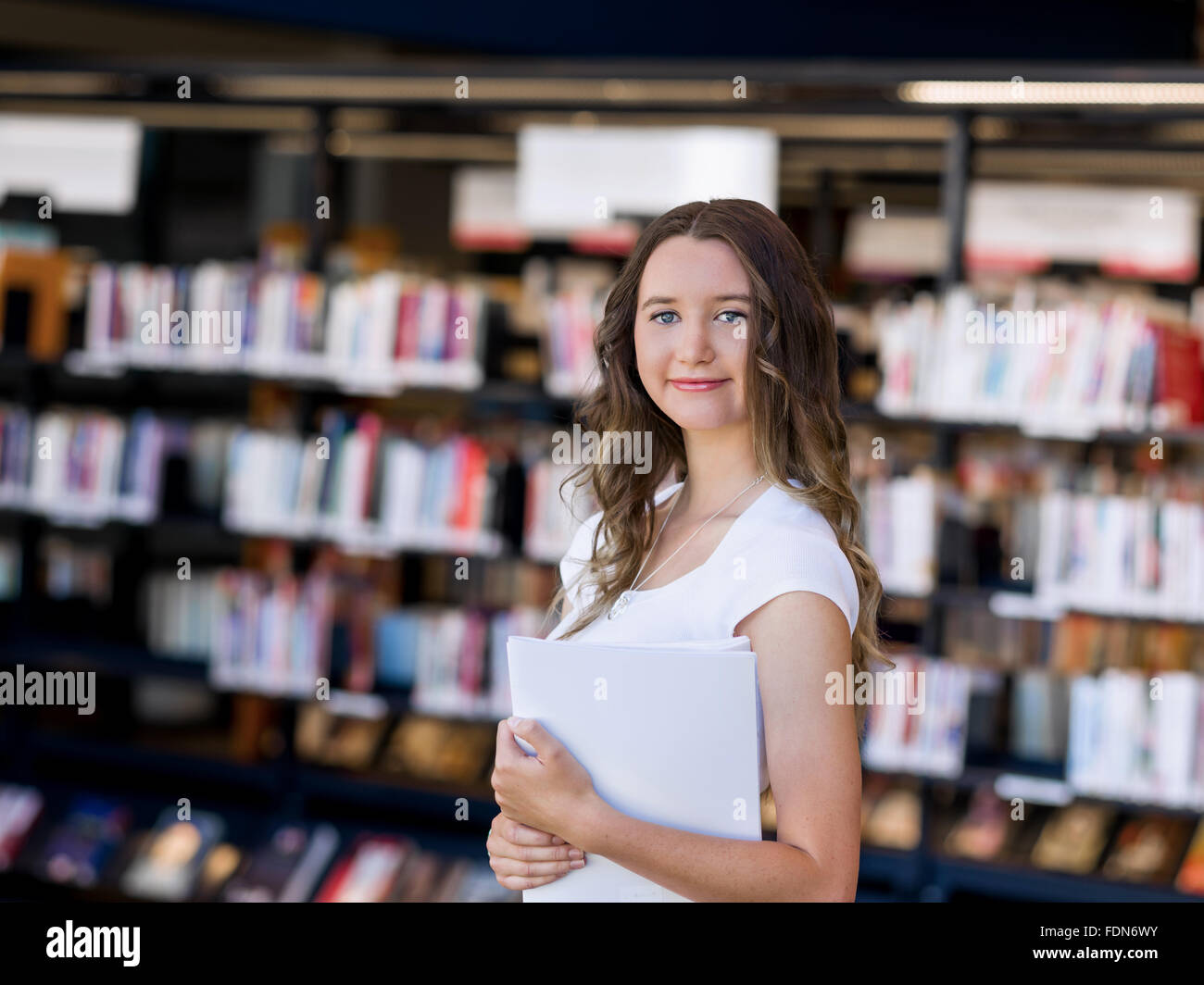 Happy young female student holding books at the library Stock Photo - Alamy