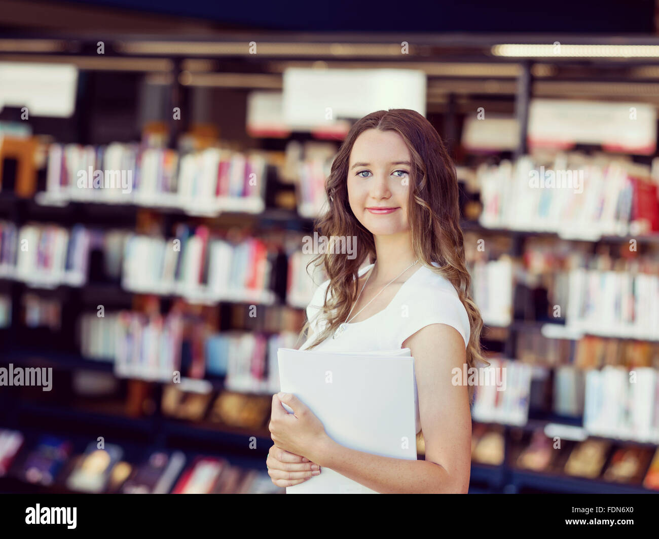 Happy young female student holding books at the library Stock Photo - Alamy