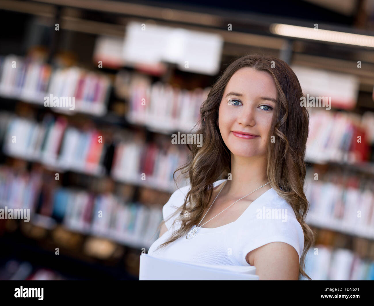Happy young female student holding books at the library Stock Photo - Alamy