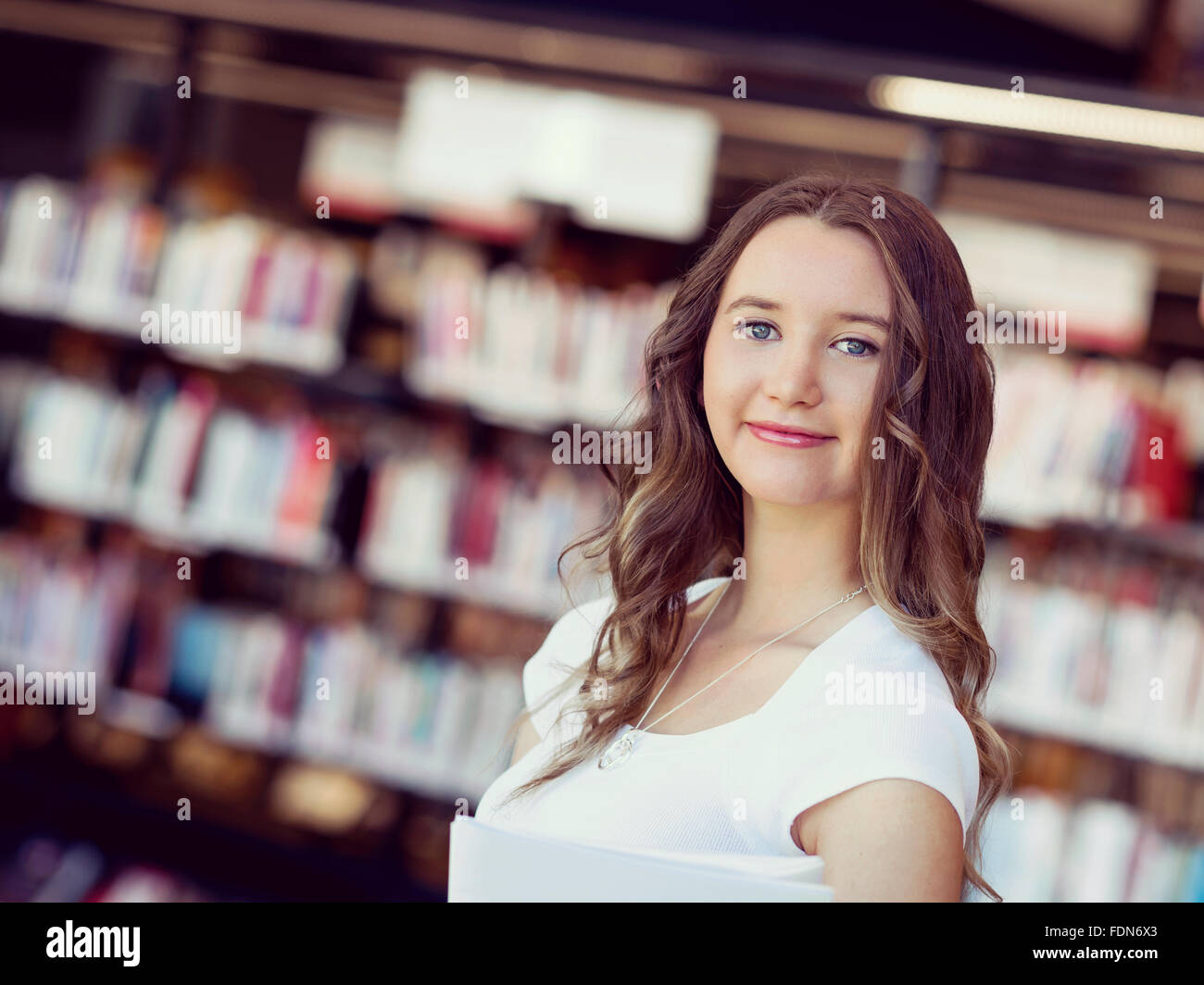 Happy young female student holding books at the library Stock Photo - Alamy