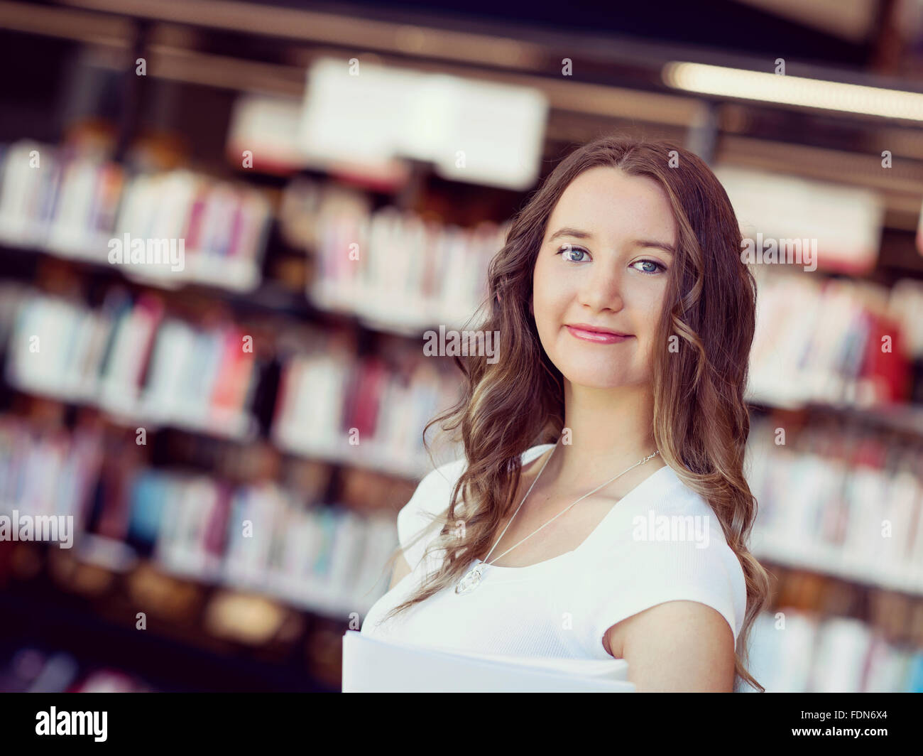 Happy young female student holding books at the library Stock Photo - Alamy