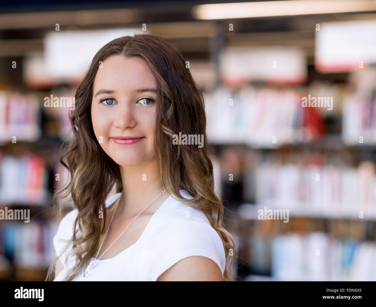 Happy young female student holding books at the library Stock Photo - Alamy