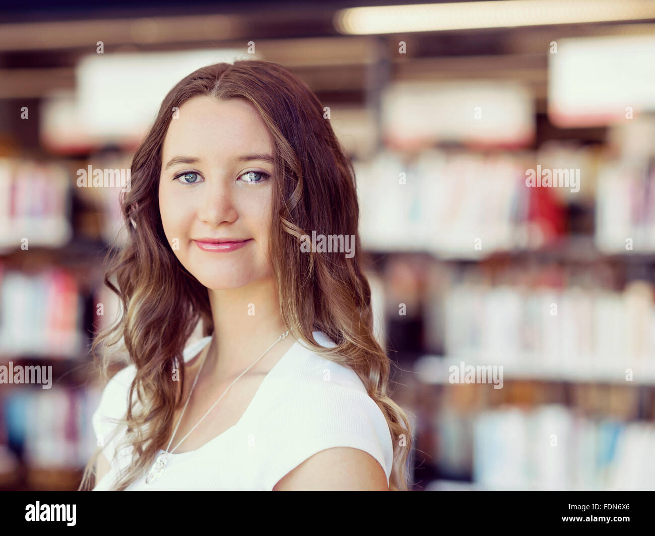Happy young female student holding books at the library Stock Photo - Alamy