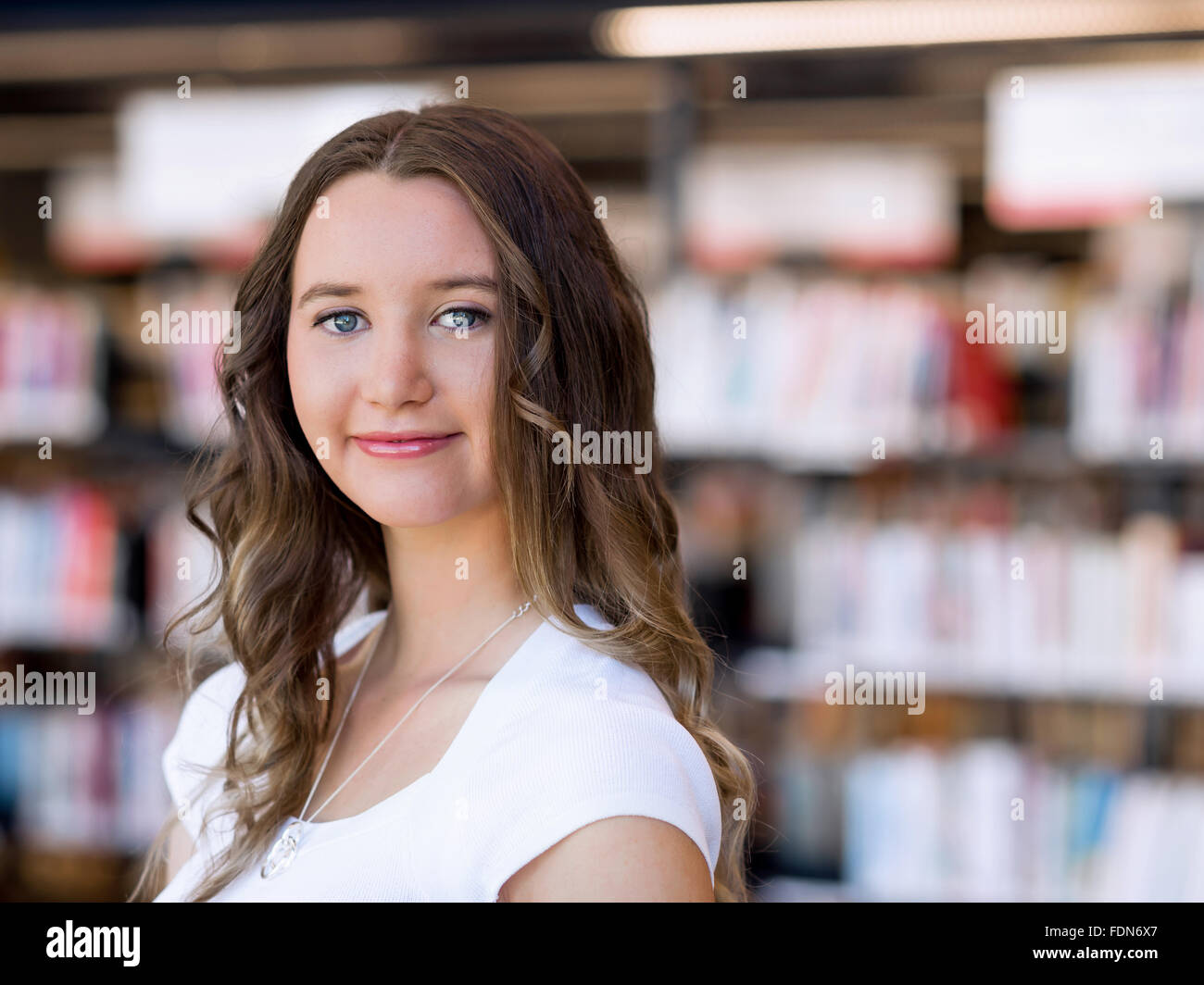 Happy young female student holding books at the library Stock Photo - Alamy