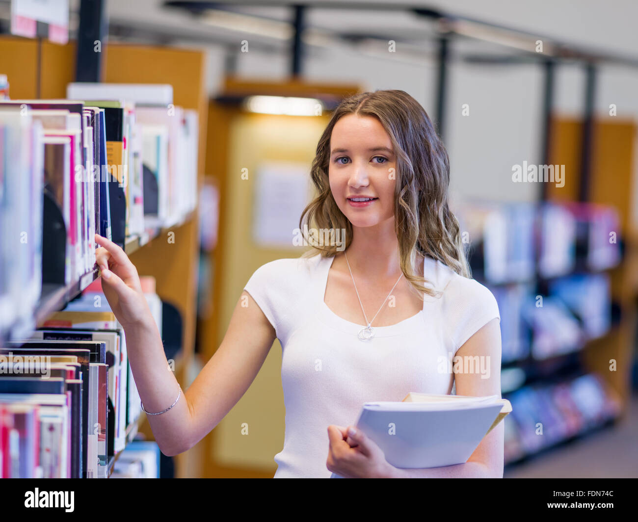 Happy young female student holding books at the library Stock Photo - Alamy
