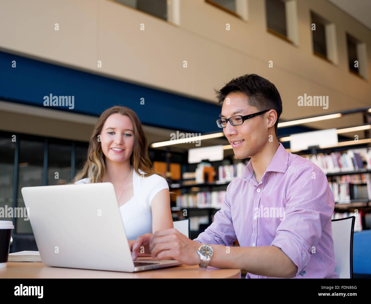 Two young students working together at the library Stock Photo - Alamy
