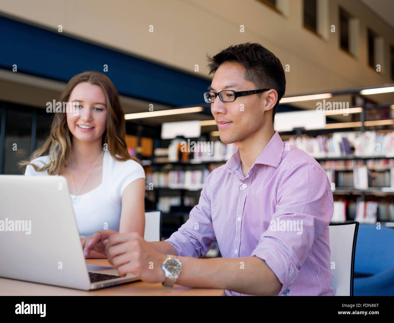 Two young students working together at the library Stock Photo - Alamy