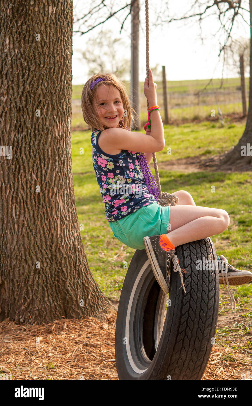 smiling Preteen girl on tire swing Stock Photo