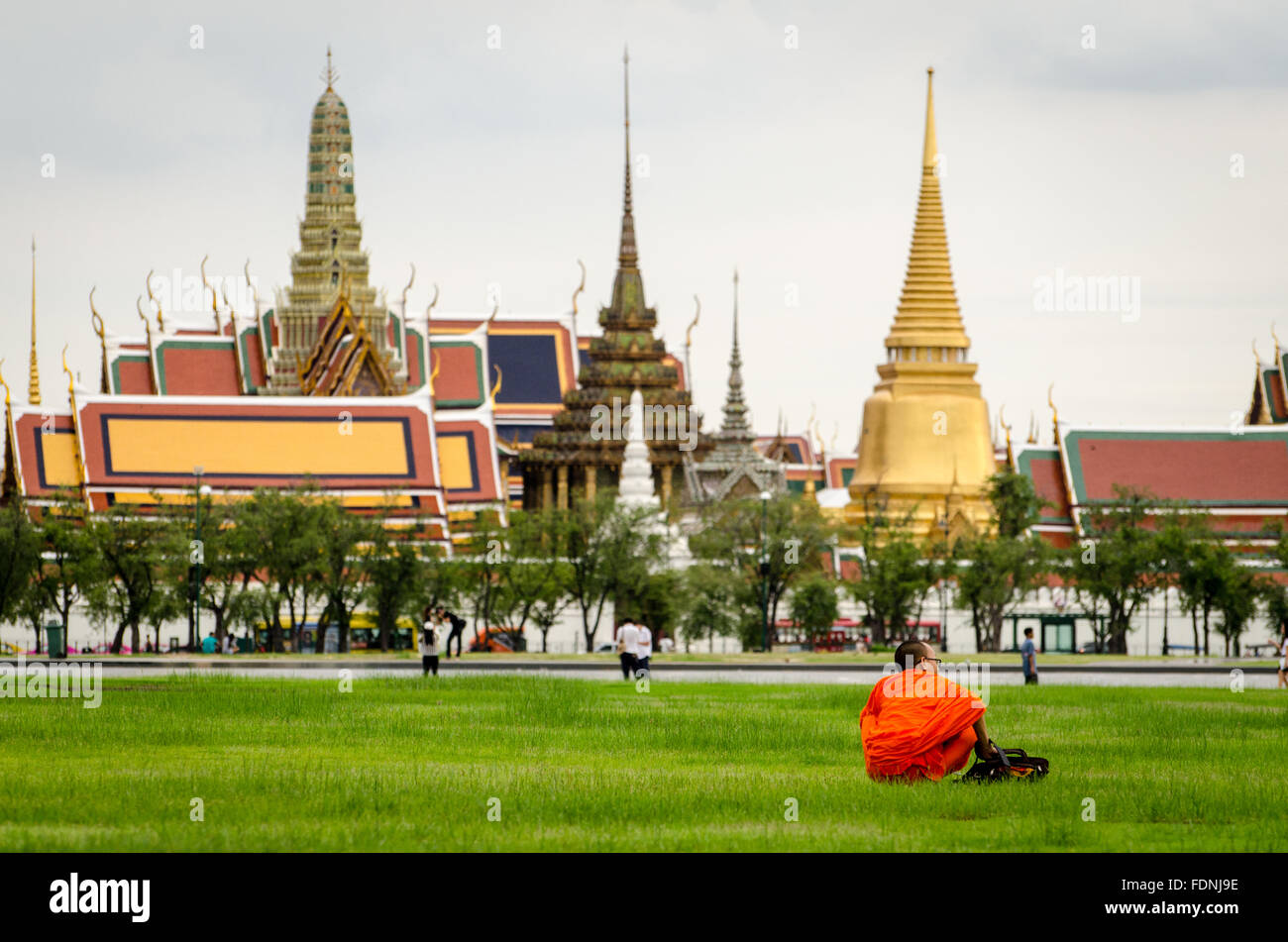 Bangkok, Bhuddist monk sitting in Sanam Luang park with Wat Phra Kaeo in the background Stock Photo
