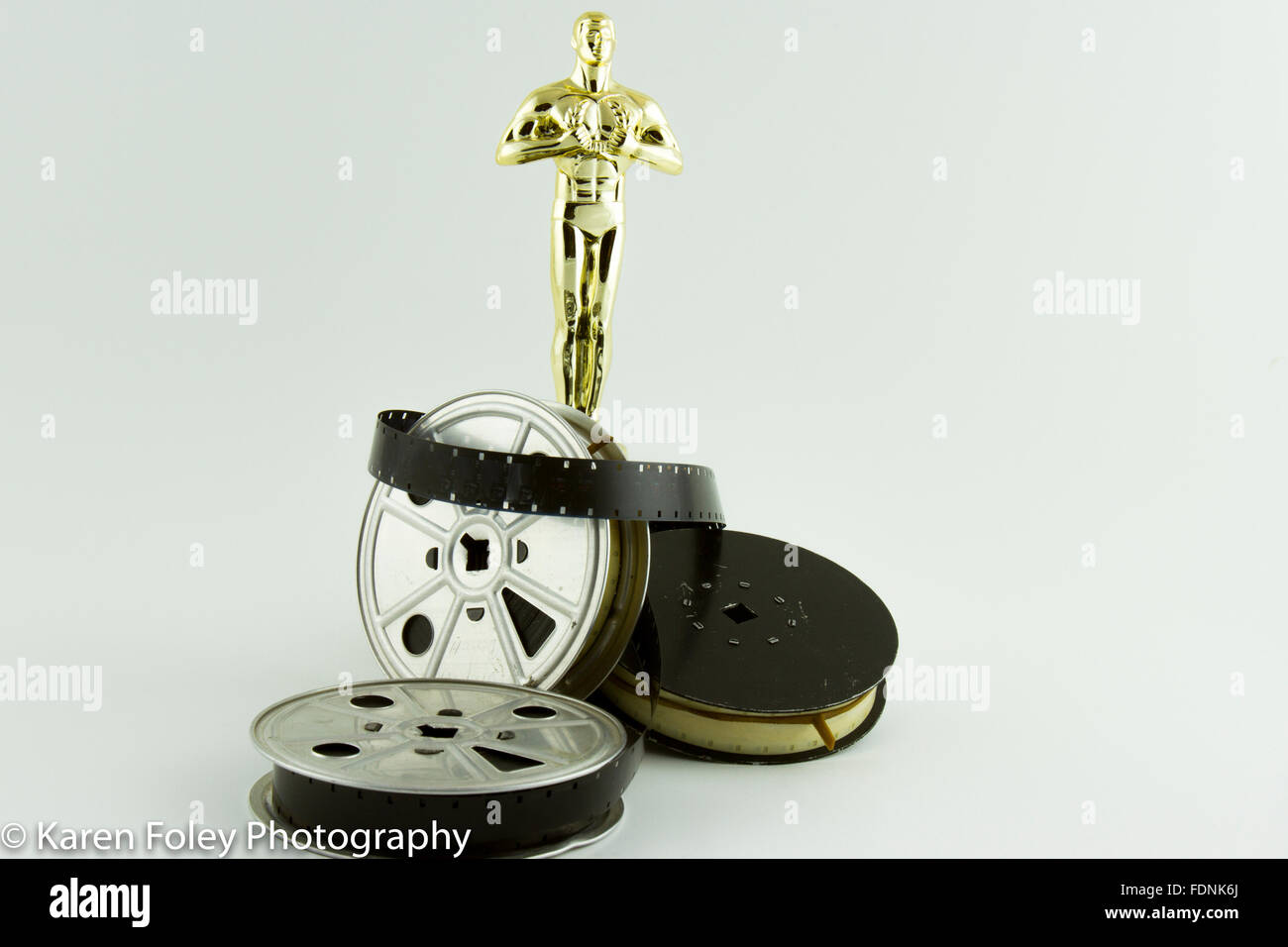 Academy Award Oscar statue with vintage movie reels on white. Stock Photo