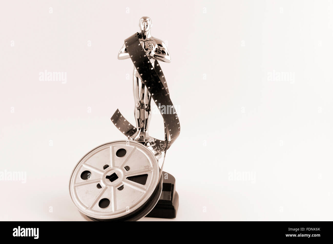 Academy Award Oscar statue with vintage movie reel desaturated with sepia tones. Stock Photo