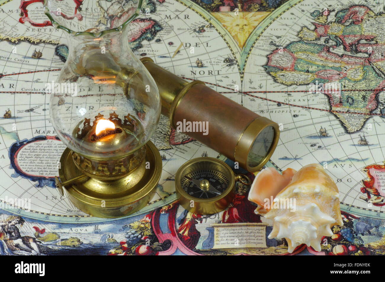 Vintage spyglass, compass, seashell and kerosene lamp lie on an old map of the world. Stock Photo