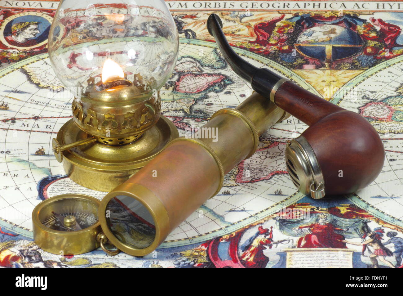 Old spyglass, pipe, compass and kerosene lamp lying on the vintage map of the world. Stock Photo
