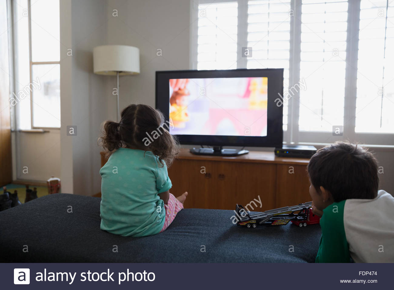 Brother and sister watching cartoons in living room Stock Photo