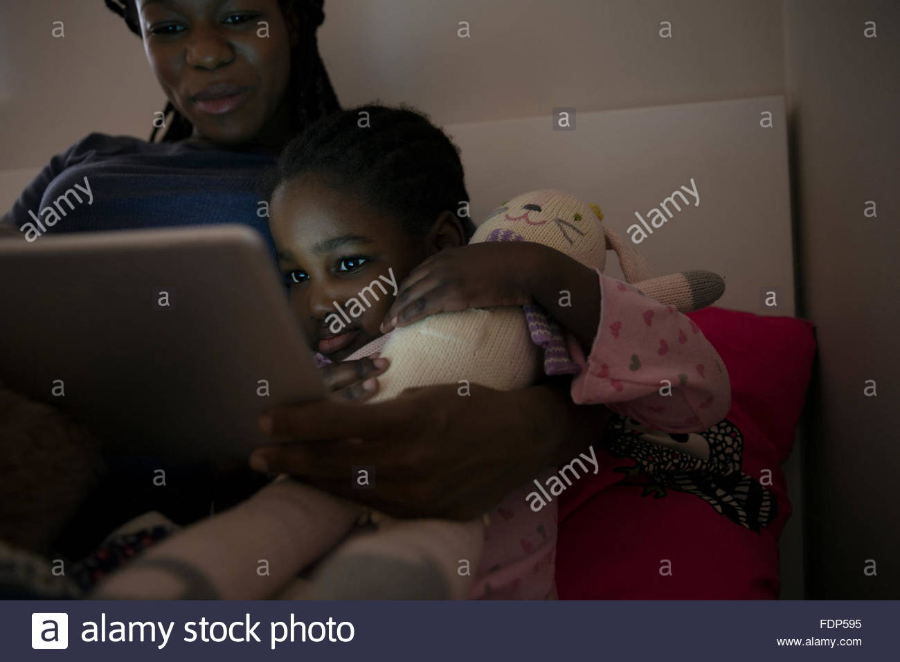 Mother and daughter using digital tablet at bedtime Stock Photo