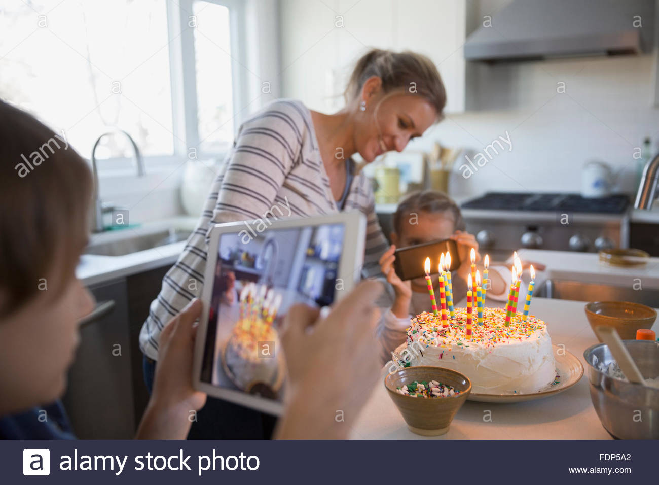 Mother and children photographing birthday cake with candles Stock Photo