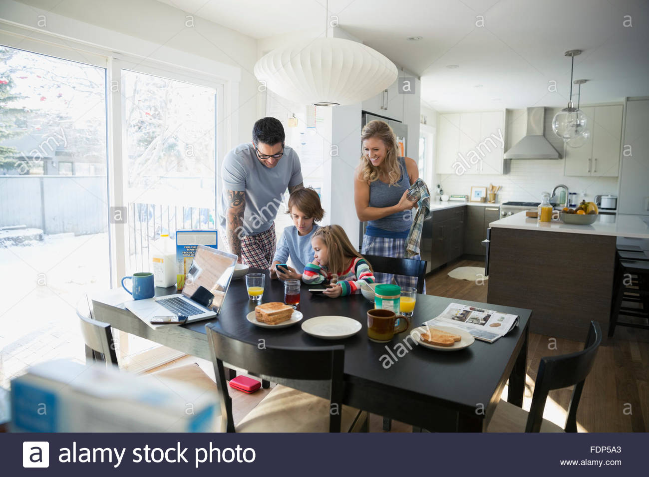 Family looking at cell phone at breakfast table Stock Photo