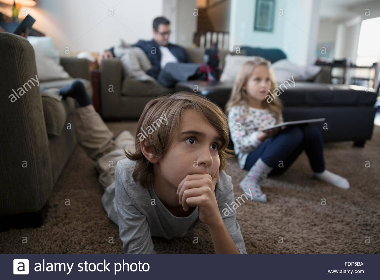 Serious boy watching TV on living room floor Stock Photo