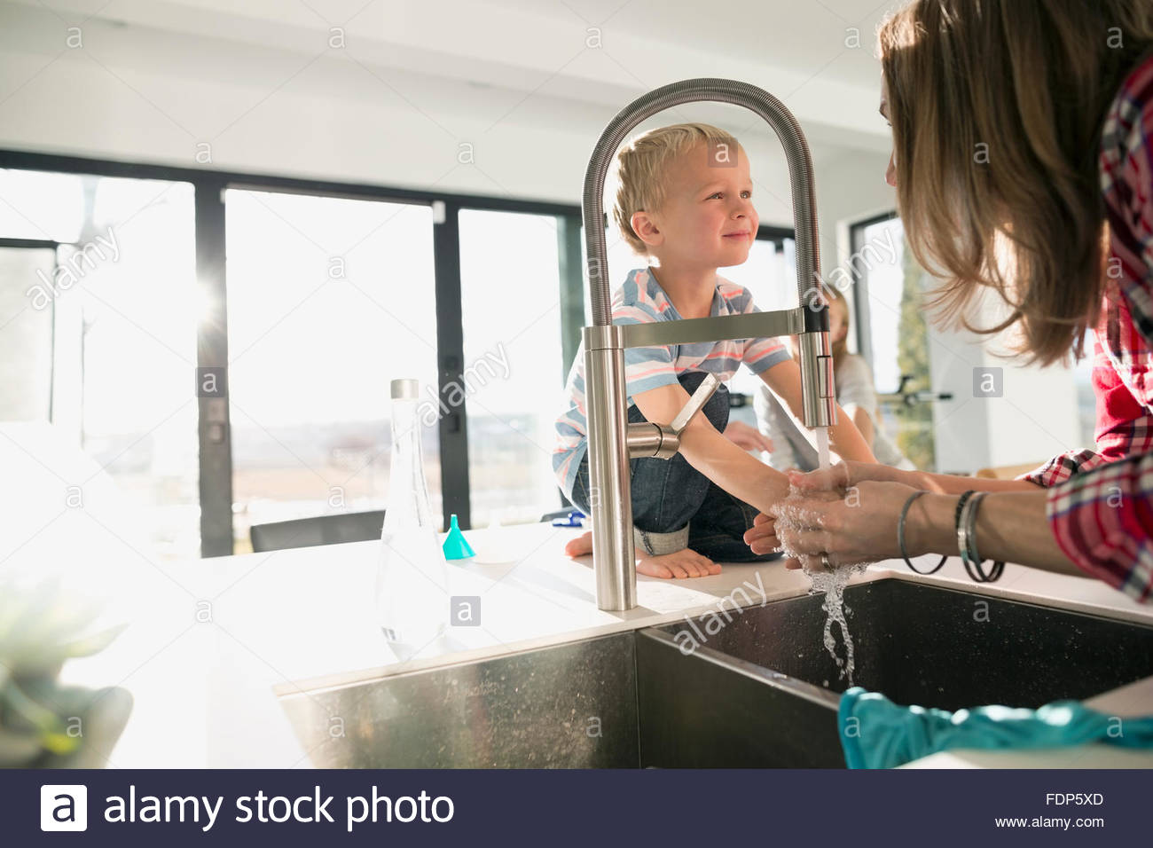 mother washing hands in kitchen sink Stock Photo Alamy