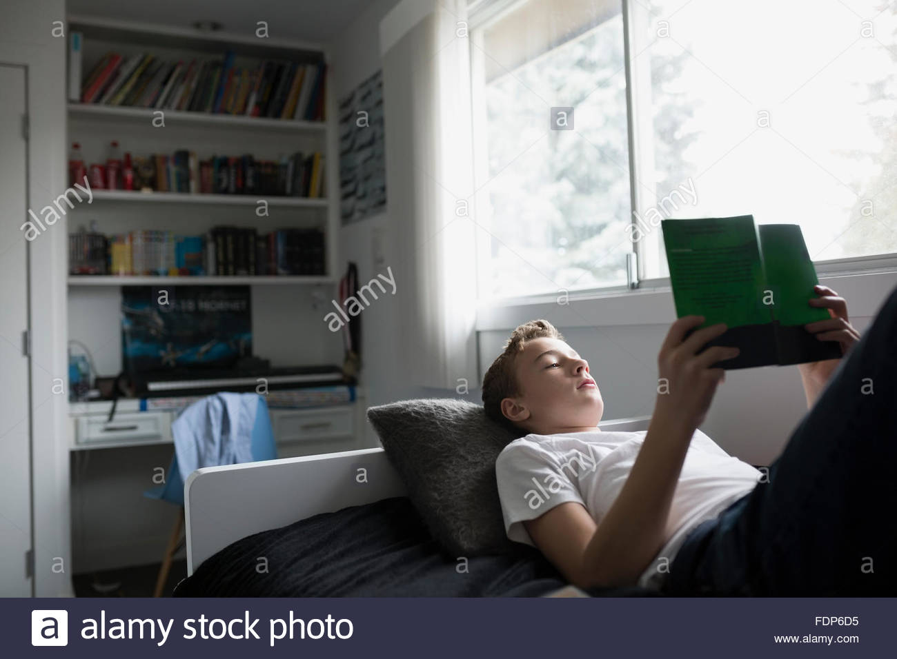 Boy reading book in bedroom Stock Photo