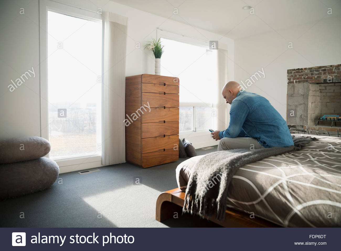 Man texting with cell phone edge of bed Stock Photo