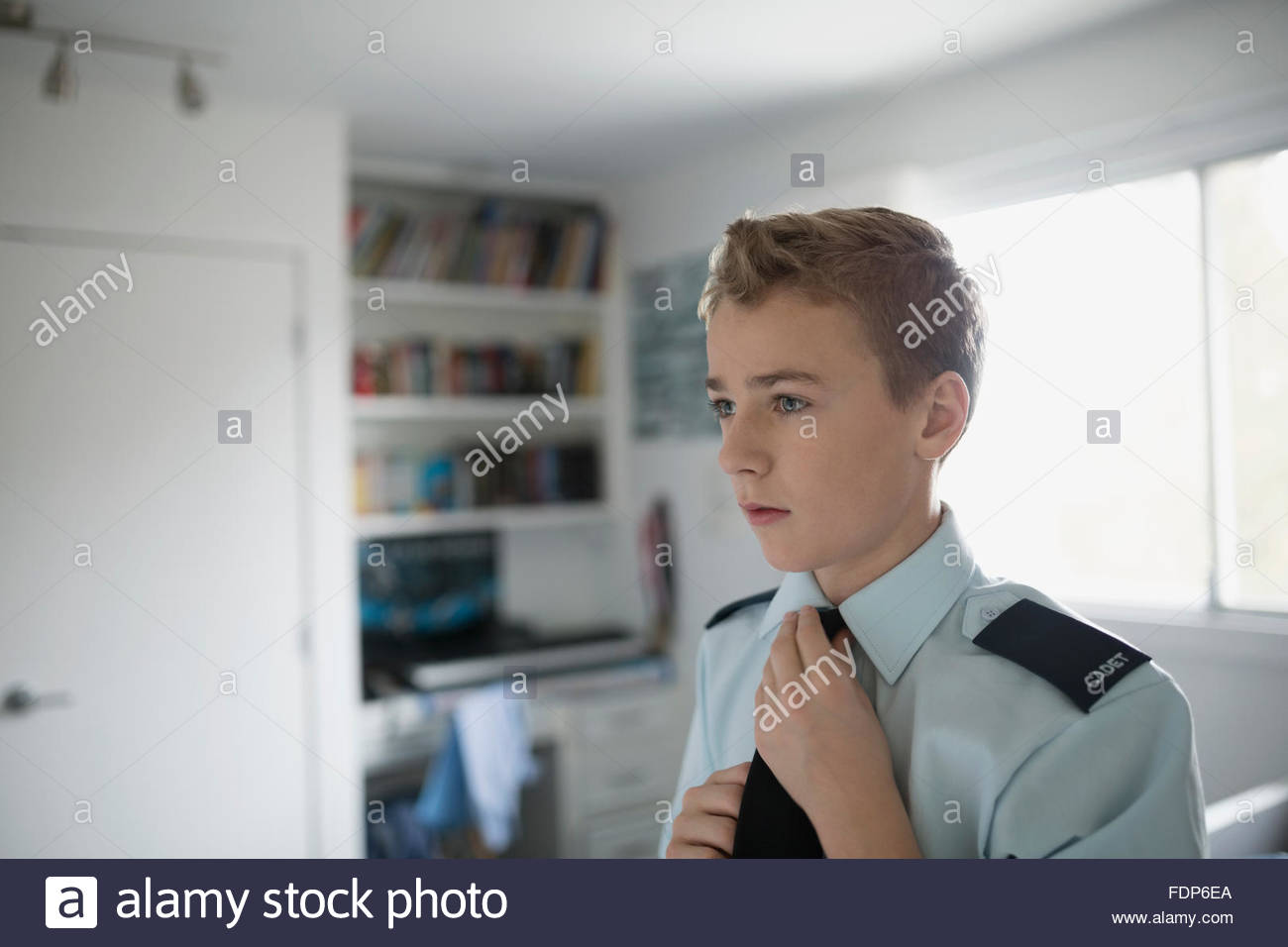 Boy adjusting cadet uniform tie Stock Photo