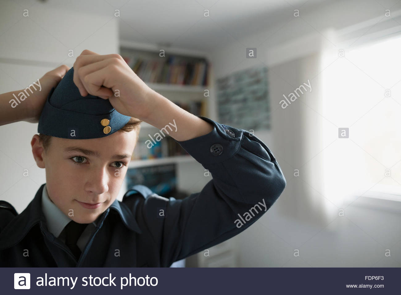 Boy putting on cadet uniform hat Stock Photo