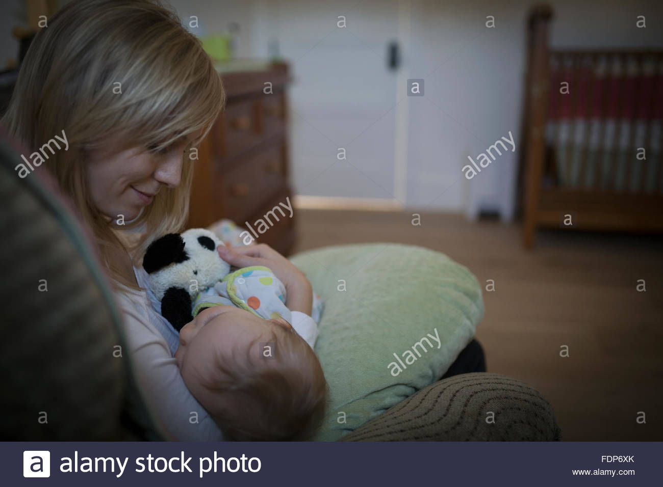 Mother holding sleeping baby son in nursery Stock Photo
