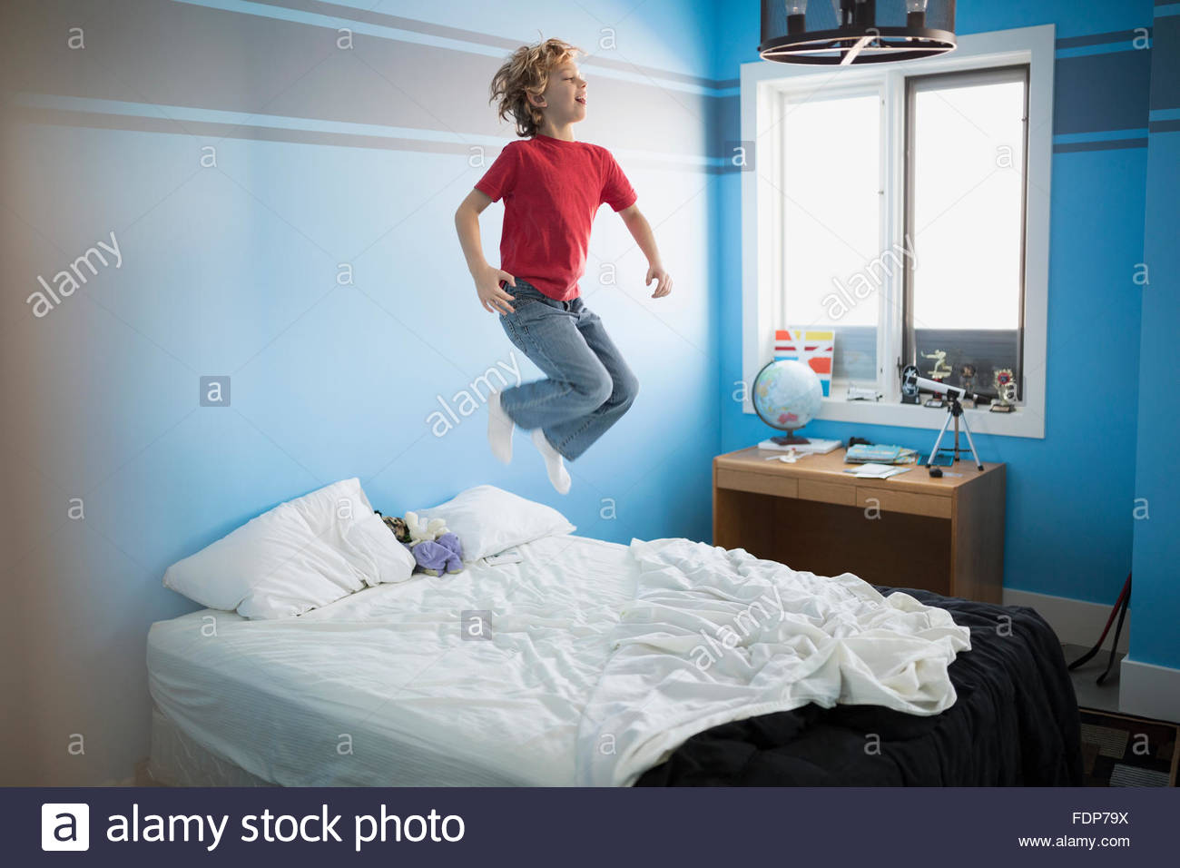 Boy jumping on bed Stock Photo