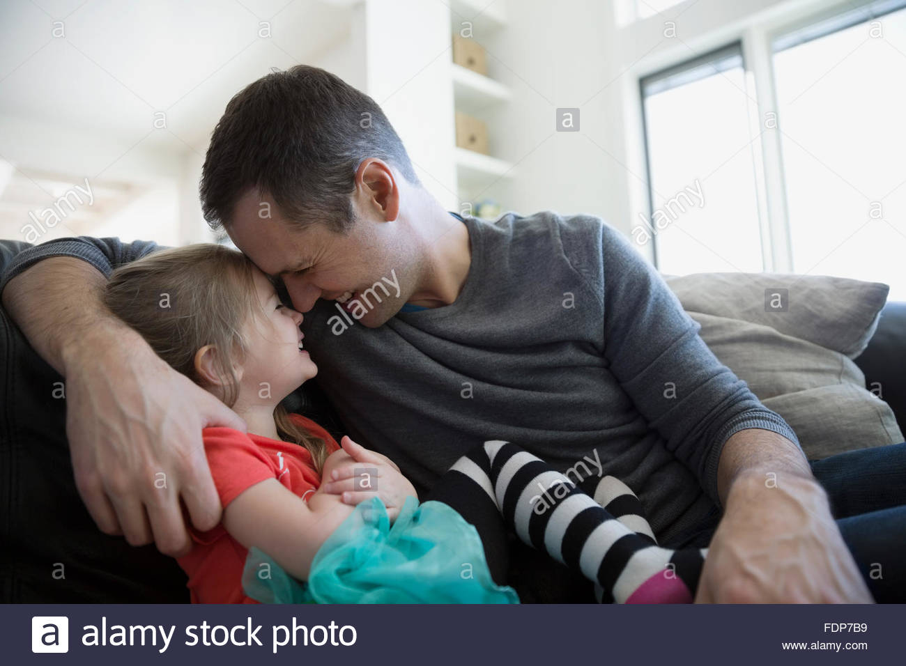Affectionate father and daughter rubbing noses on sofa Stock Photo