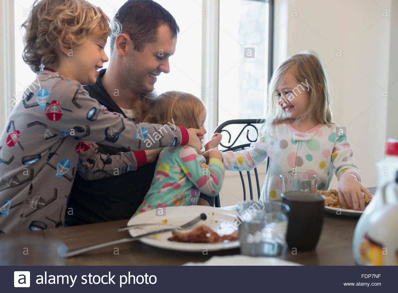 Playful father and children at breakfast table Stock Photo