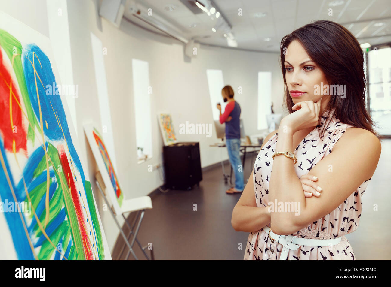 Young caucasian woman standing in an art gallery in front of painting ...