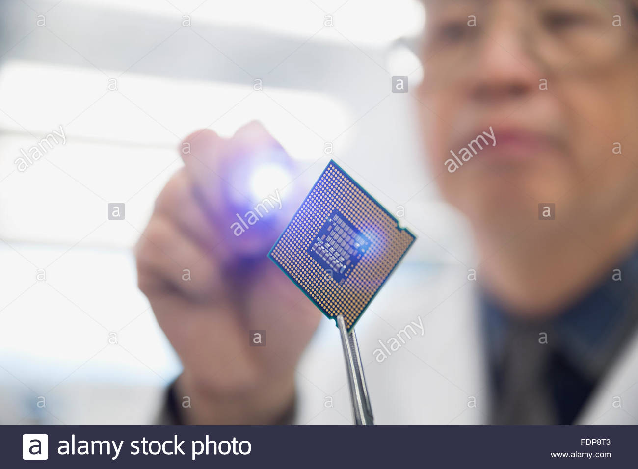 Focused engineer examining microchip with flashlight Stock Photo