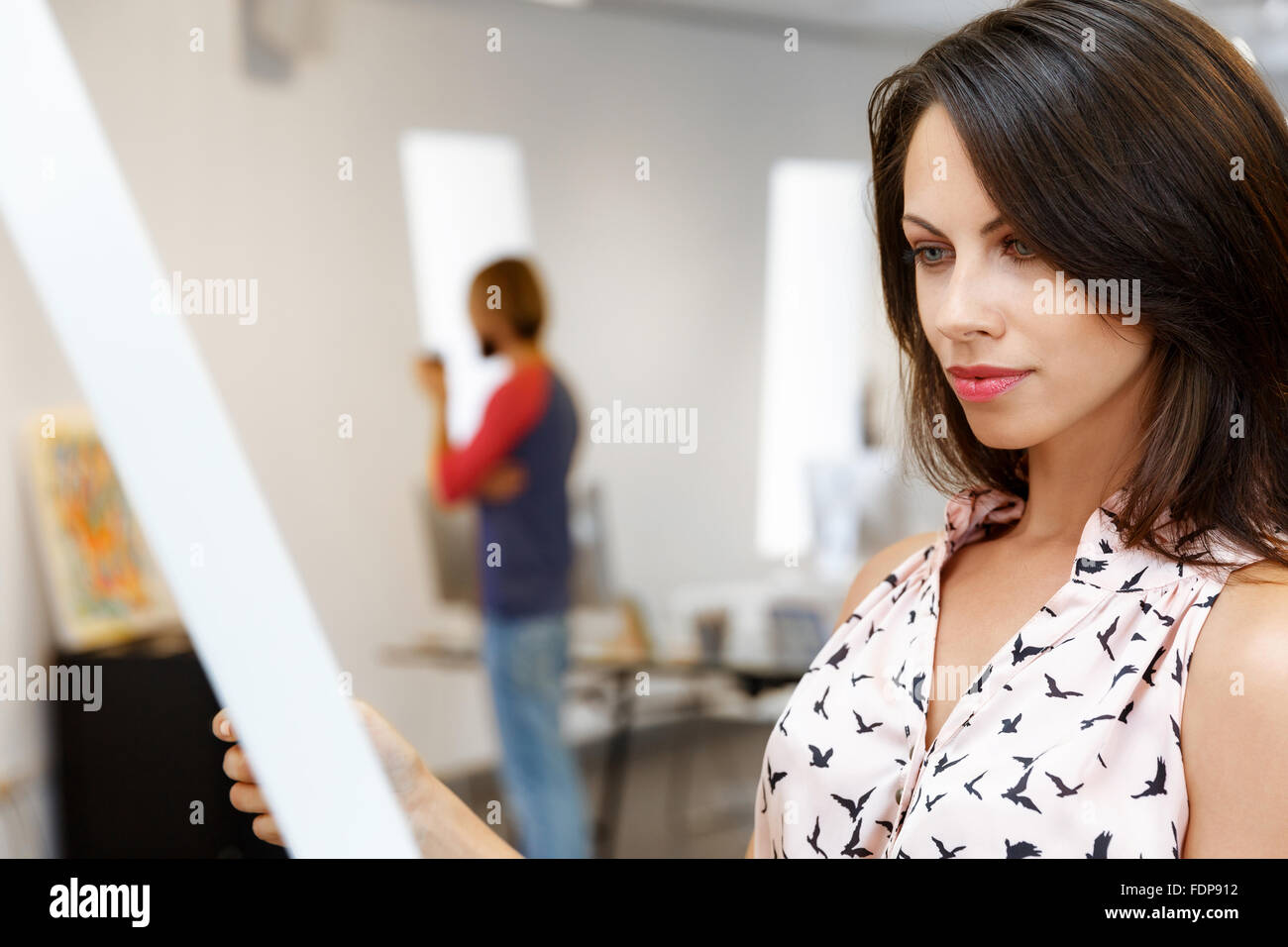 Young caucasian woman standing in an art gallery in front of painting ...