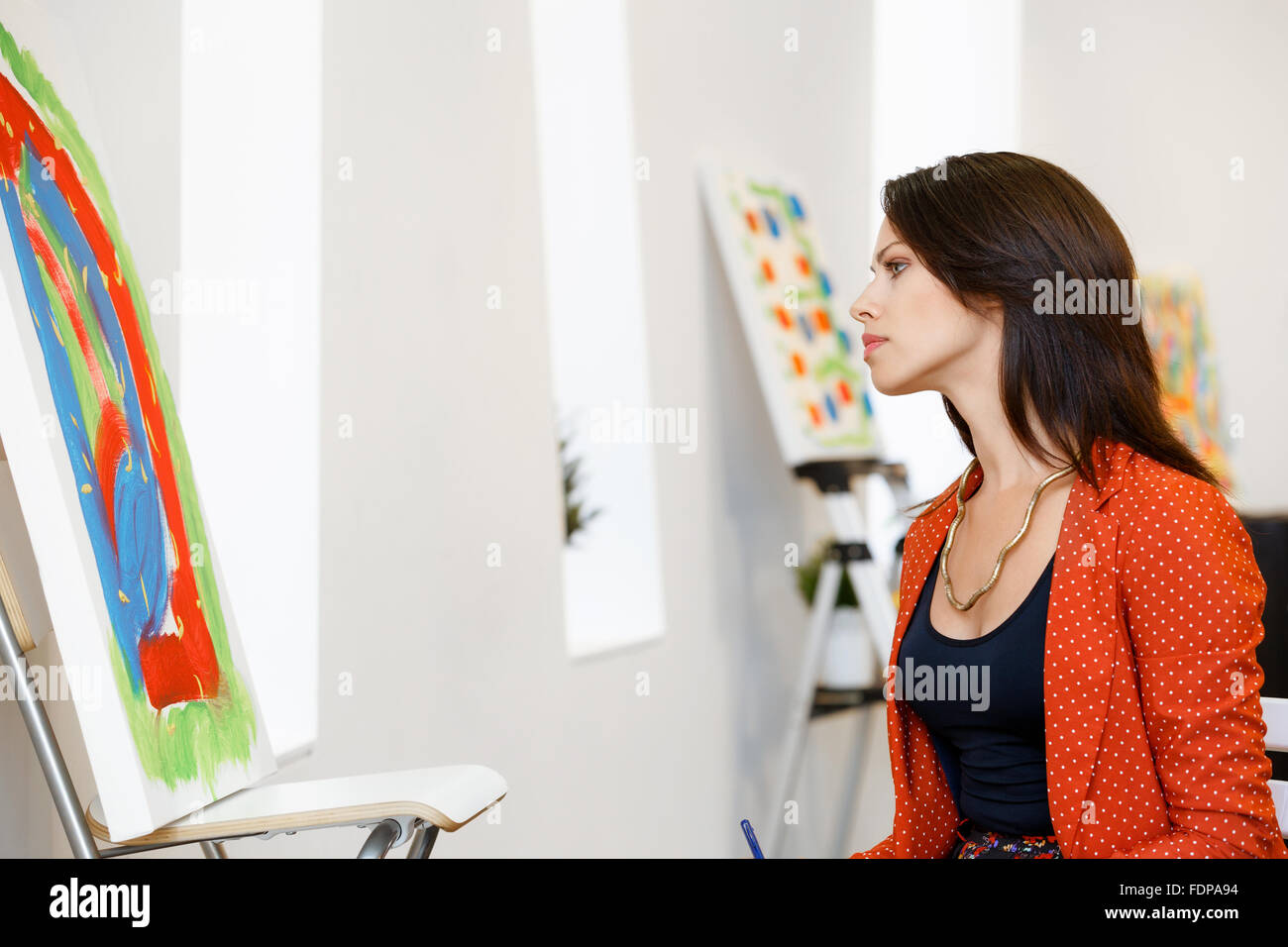 Young caucasian woman standing in an art gallery in front of painting ...