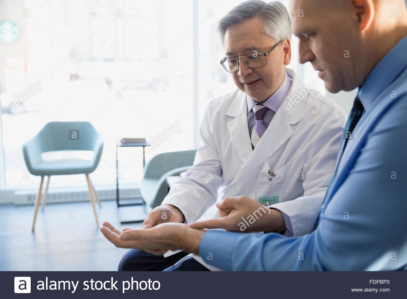 doctor checking patient wrist clinic lobby 45-49 Stock Photo