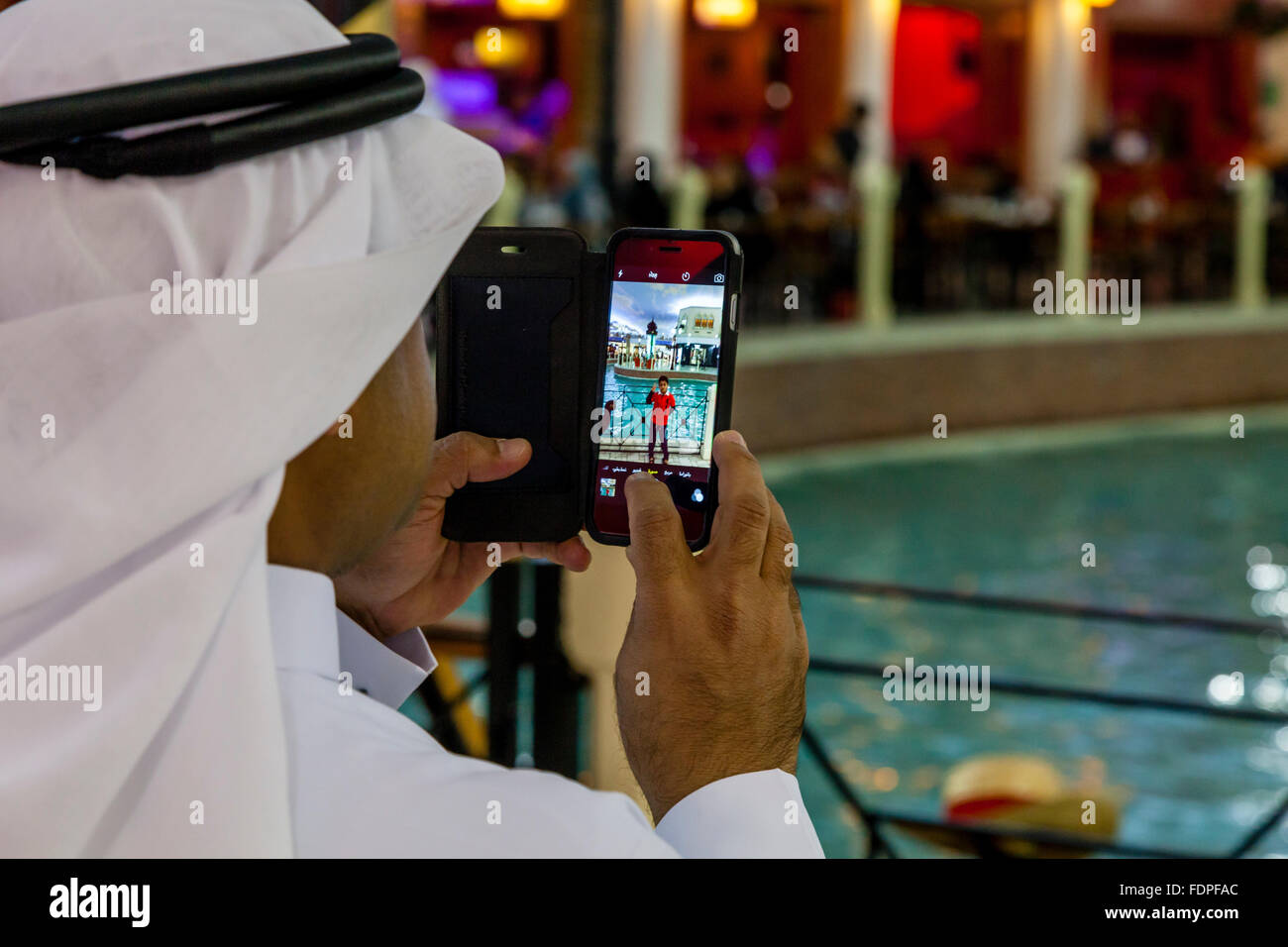 A Local Man Takes Photos Of His Family On His Cell/Mobile Phone, Villaggio Shopping Mall, Doha, Qatar Stock Photo