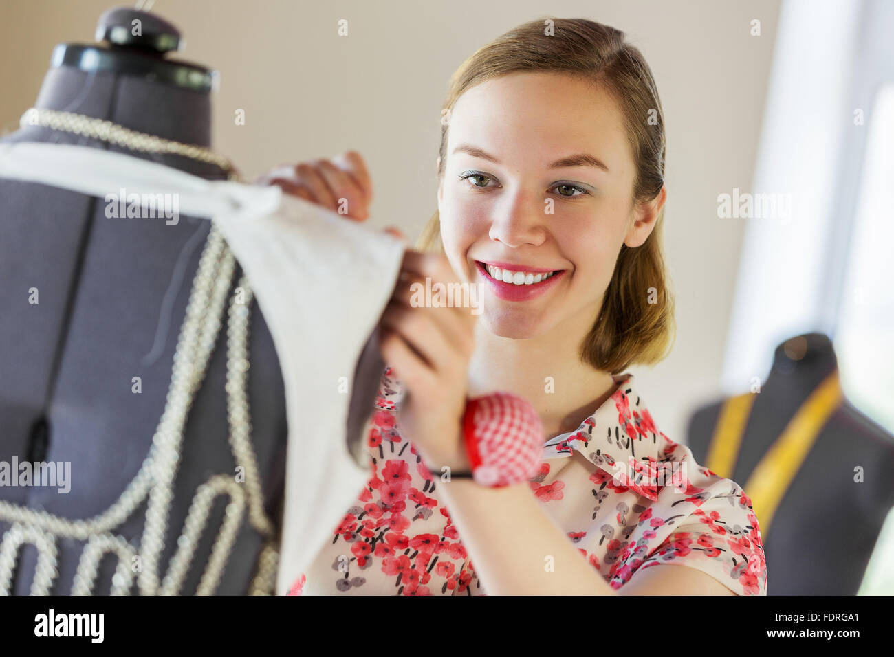Pretty dressmaker at work pinning dress on dummy Stock Photo Alamy
