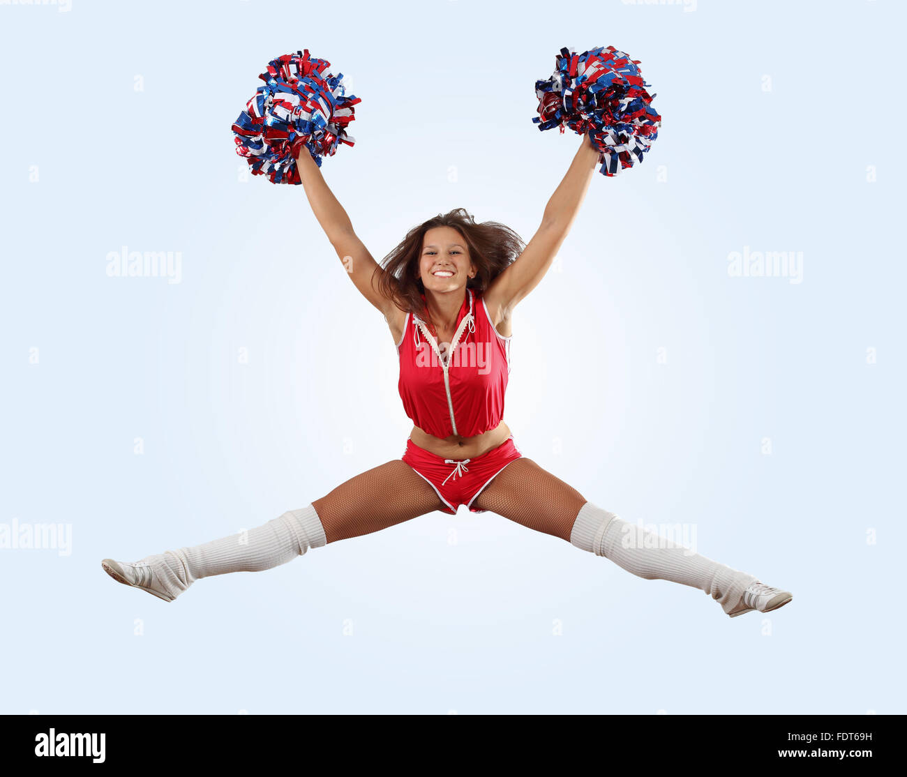 Uniformed cheerleader jumps high in the air isolated on white Stock