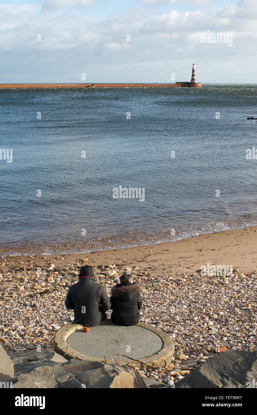 Retired couple sitting looking out to sea at Roker, Sunderland, north east England, UK Stock Photo