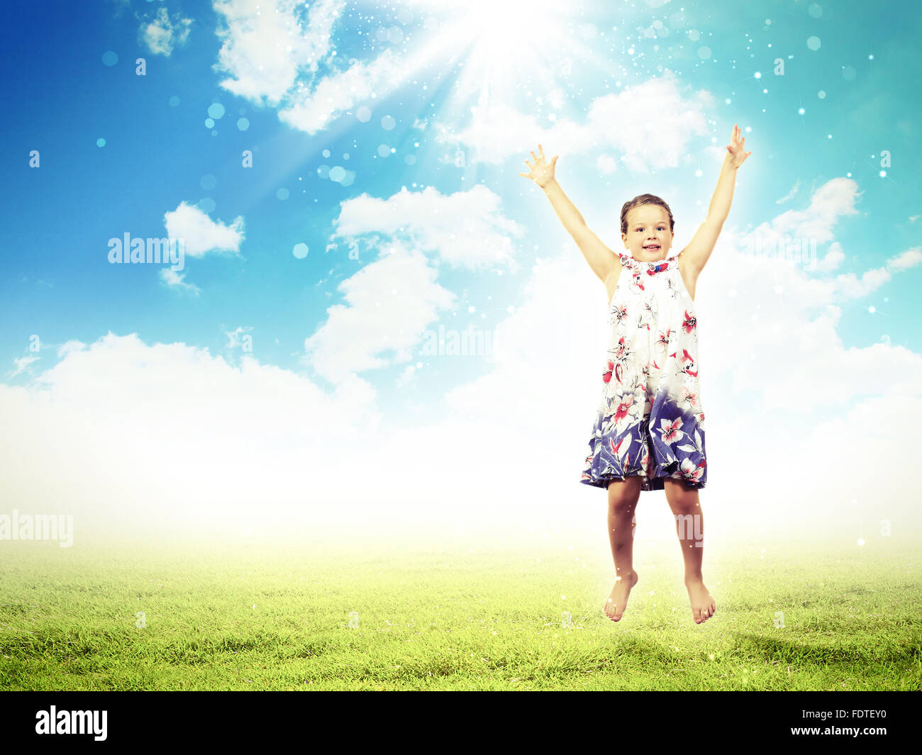 Photo of little girl jumping and raising hands against nature ...