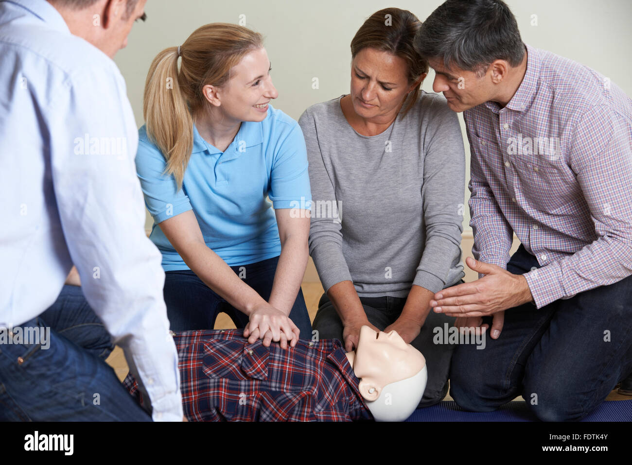 Woman Demonstrating CPR On Training Dummy In First Aid Class Stock Photo