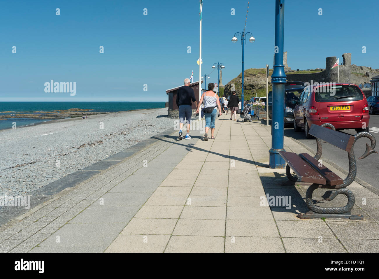 A couple walking hand in hand along the esplande by Aberystwyth's shingle beach. Stock Photo