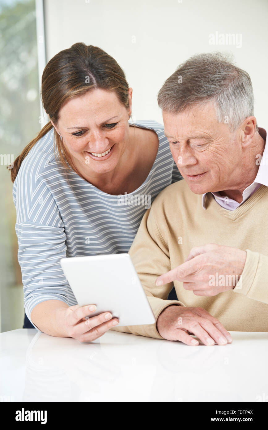 Senior Man And Adult Daughter Looking At Digital Tablet Together Stock Photo