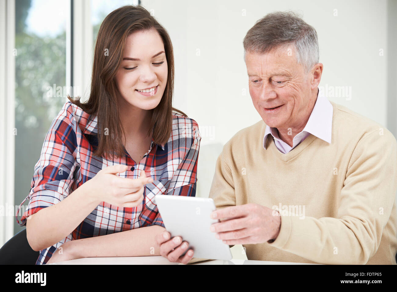 Teenage Granddaughter Showing Grandfather How To Use Digital Tablet Stock Photo