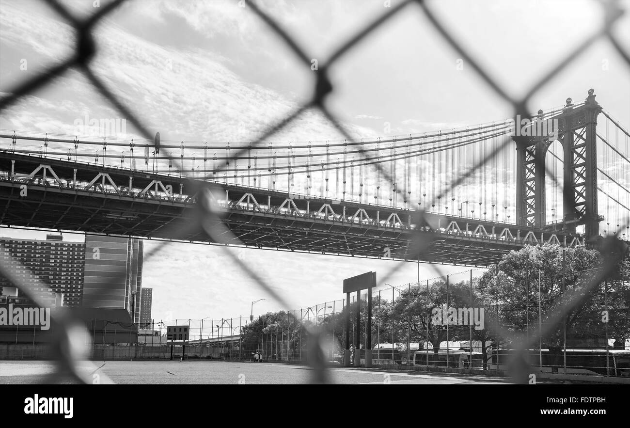 Manhattan Bridge seen through sport field fence, old film style, NYC, USA. Stock Photo