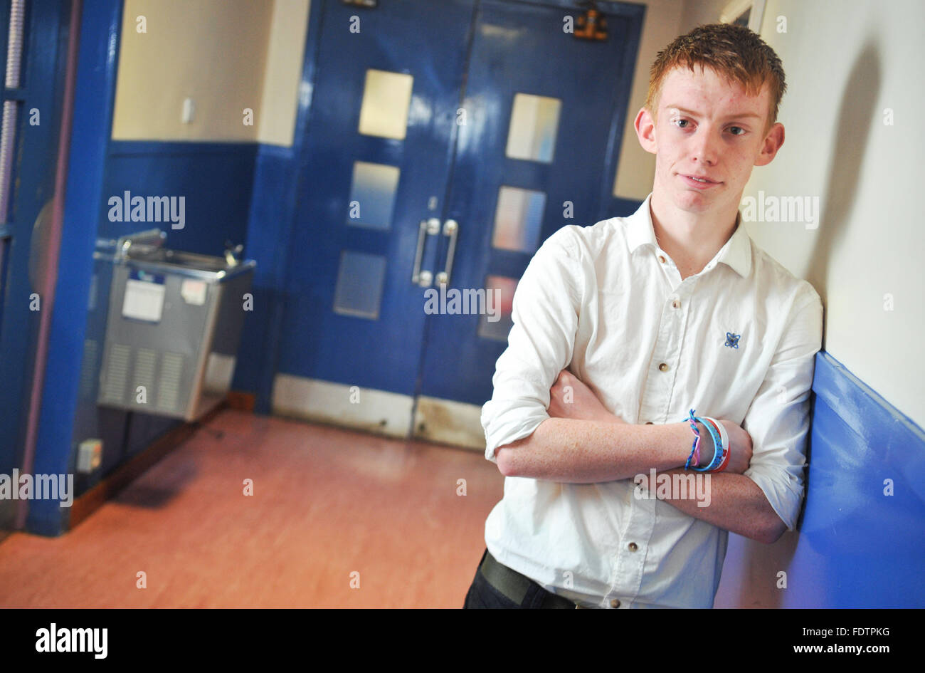 Ginger teenage boy school pupil poses in corridor. Stock Photo